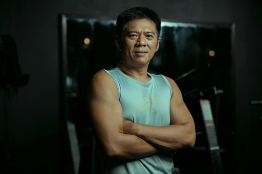 Fit man standing in the gym with arms crossed.