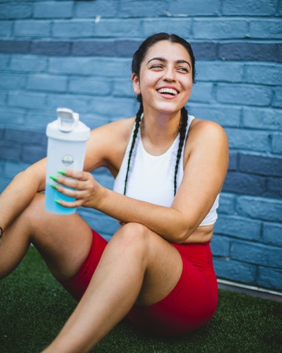 woman in white tank top and red shorts holding white plastic bottle